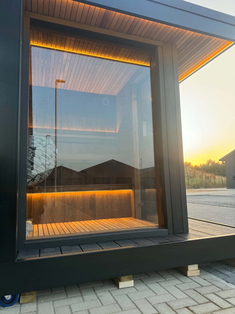 Outdoor sauna with full-height glass front at sunset